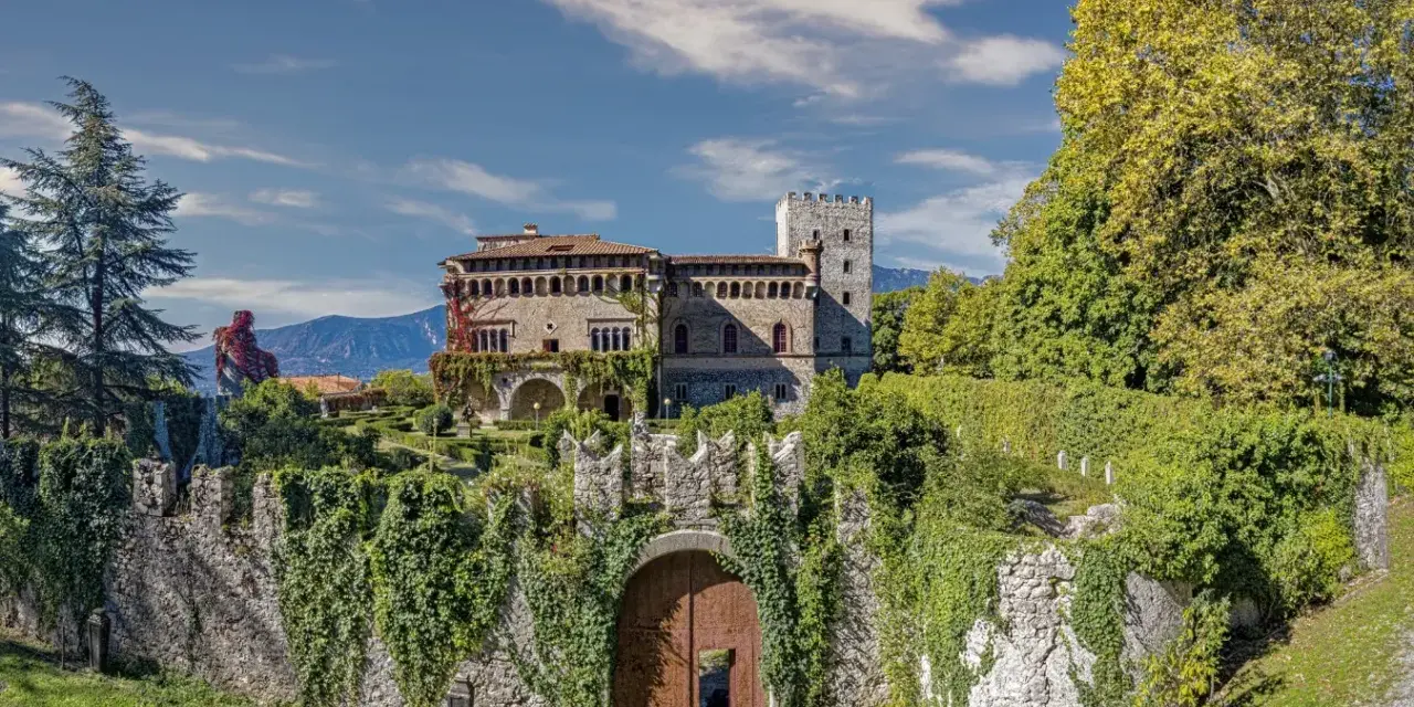 Villa d'Ayala, un castello incantevole con torri e giardini lussureggianti, immerso tra le montagne sotto un cielo azzurro.