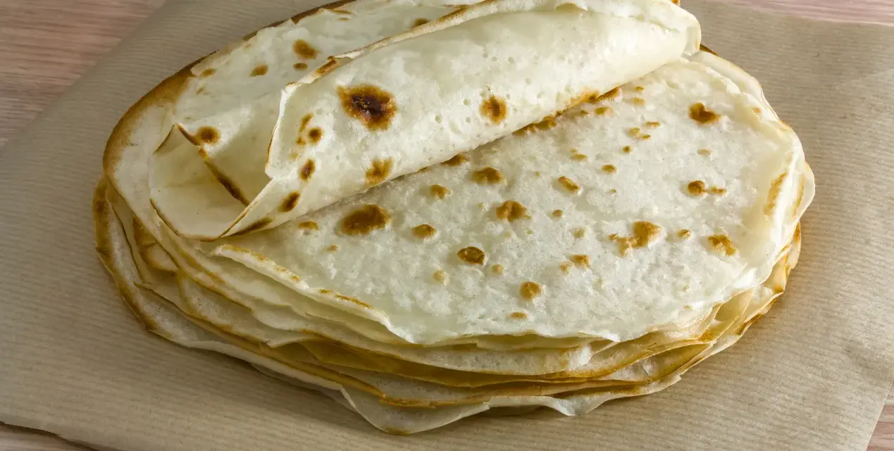 Impasto piadina appena cotto, impilato su carta da forno. Le sottili sfoglie dorate invitano a essere farcite.