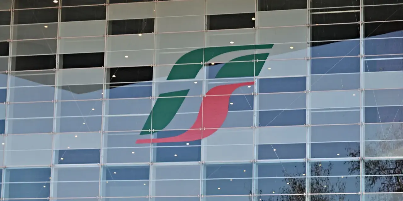 Logo Trenitalia su facciata di vetro. Un'immagine che ricorda il rimborso Trenitalia per ritardi o disservizi.