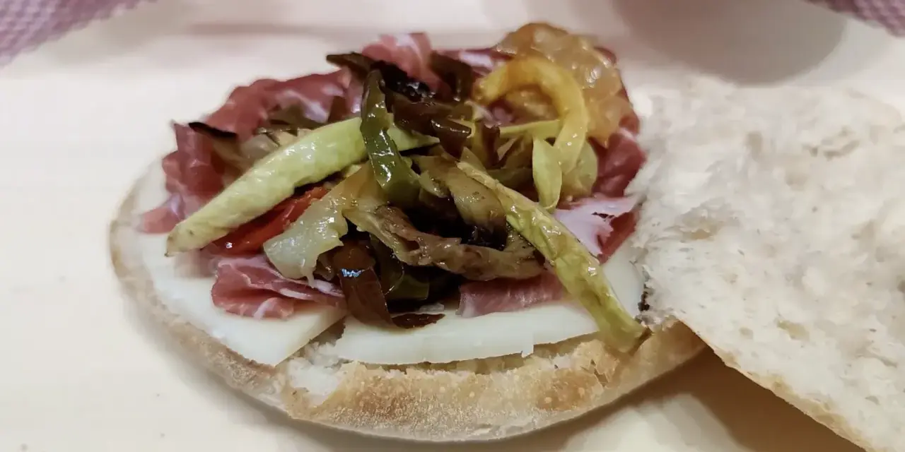 Puccia leccese con salumi, formaggio e verdure grigliate, un sapore autentico del Salento.