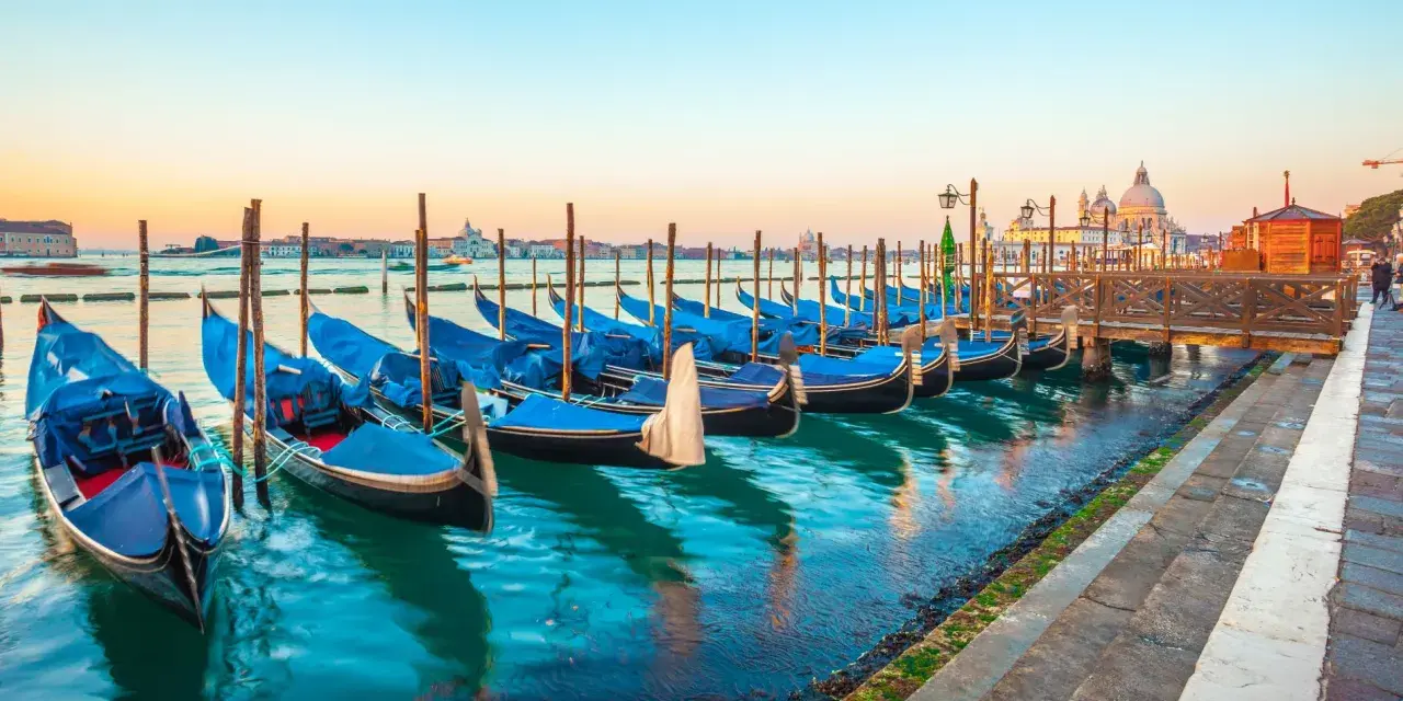 Gondole blu ormeggiate a Venezia, un modo suggestivo per muoversi spendendo poco.