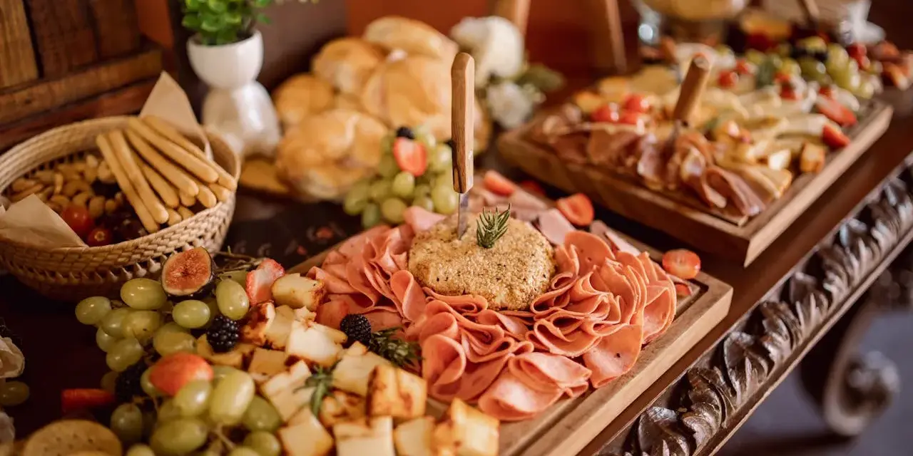 Un ricco buffet con salumi, formaggi, frutta e pane, un vero banchetto che fa pensare alla pensione completa significato: tutto incluso per godersi il momento.