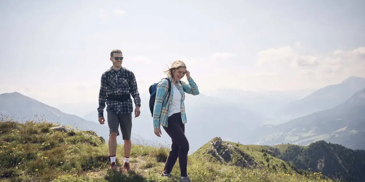 Coppia escursionista sorridente in montagna. L'aria di montagna fa bene al raffreddore, rigenera corpo e mente.