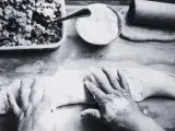 Mani esperte modellano la pasta per creare un'azdora romagnola, con ripieno e farina pronti.