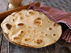 Piadine pronte per essere farcite, con un matterello e un canovaccio a quadretti. Si può fare l'impasto della piadina il giorno prima per comodità.