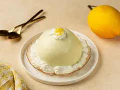 Dolce al limone, perfetto per scoprire cosa mangiare a Salerno. Servito con panna e scorzetta, pronto per essere gustato con cucchiaini dorati.