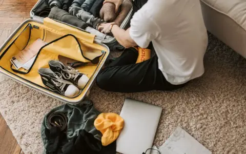 Preparazione per il viaggio: cosa si può portare in aereo. Valigia aperta con scarpe, vestiti, laptop e mappa.