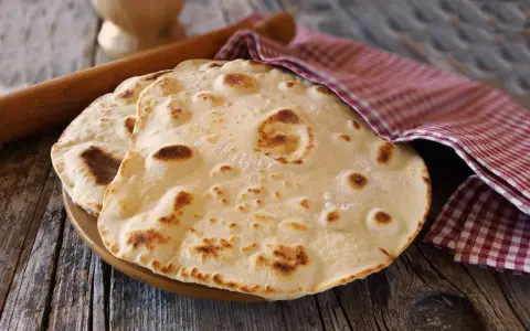 Piadine pronte per essere farcite, con un matterello e un canovaccio a quadretti. Si può fare l'impasto della piadina il giorno prima per comodità.