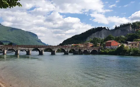 Ponte storico sul fiume Adda, con montagne verdi e case colorate. Un'ottima vista per scoprire cosa vedere a Calolziocorte.