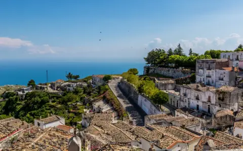 Panoramica di un borgo collinare con vista mare. Per raggiungere l'università Monte Sant'Angelo Napoli, si percorre una strada tortuosa tra case antiche.