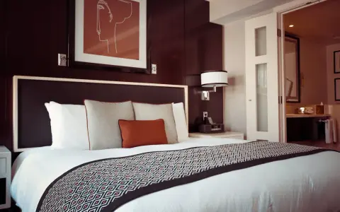 Letto in una camera doppia, con copriletto geometrico e quadro astratto. Il significato di camera doppia è un luogo accogliente.