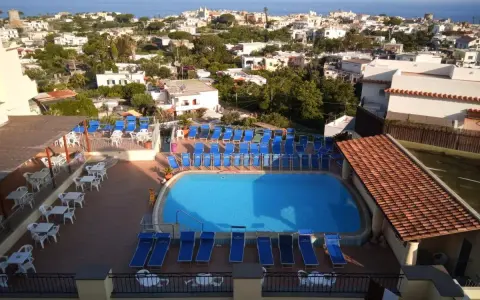 Piscina e lettini prendisole al **hotel tramonto Ischia**, con vista sul mare e sul paese.