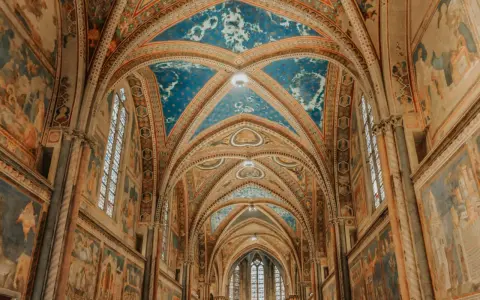 Volte affrescate con cielo stellato e scene sacre nella Basilica Superiore di San Francesco, cuore del centro storico di Assisi.