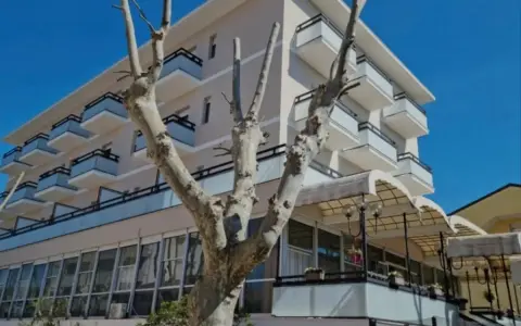 Edificio moderno con balconi e vetrate, un albero spoglio in primo piano. Il **Kursaal Bellaria** si presenta sotto un cielo azzurro.