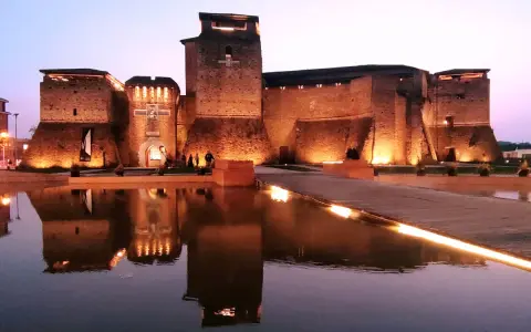 Castello illuminato di sera, riflesso sull'acqua. Un luogo magico che evoca il mondo di Fellini.
