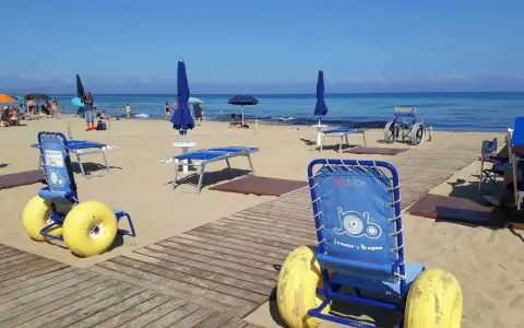 Carrozzine speciali e passerelle per vacanze per disabili con assistenza su una spiaggia attrezzata.