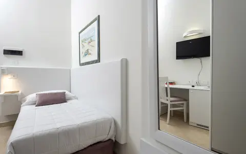 Accogliente camera singola hotel con letto, scrivania e TV visibili nello specchio.
