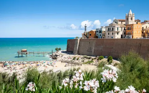 Vista di una spiaggia affollata con un trabucco sul mare e il borgo antico di Termoli. Perfetto per scoprire cosa vedere vicino a Termoli.