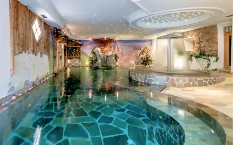 Piscina interna con cascata e decorazioni naturali, un'oasi di relax all'Hotel Sporting Andalo.