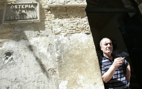 Uomo fuma davanti alla trattoria Angiolino a Lecce.