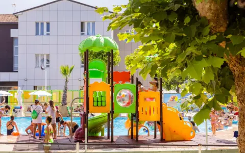Bambini giocano in piscina e su uno scivolo colorato, un'immagine che riflette le positive recensioni di Color Perla Village.