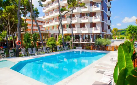 Piscina azzurra e lettini prendisole davanti al **promenade hotel giulianova**, circondati da pini e vegetazione lussureggiante.