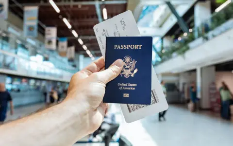 Passaporto USA e boarding pass pronti per il viaggio. L'aeroporto fa da sfondo.
