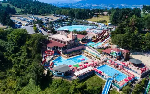 Un grande parco acquatico nelle Marche, con scivoli, piscine e tante persone che si divertono sotto il sole.