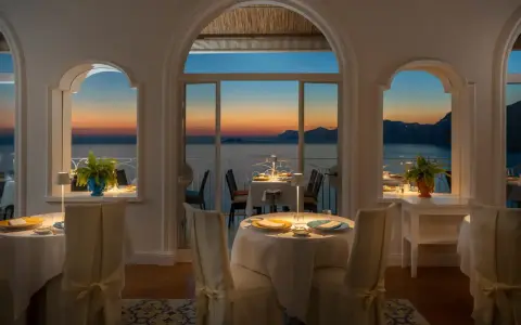Tavoli apparecchiati nel ristorante dell'hotel Tramonto d'Oro, con vista sul mare al tramonto.