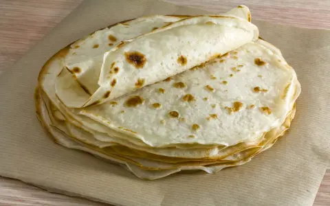 Impasto piadina appena cotto, impilato su carta da forno. Le sottili sfoglie dorate invitano a essere farcite.