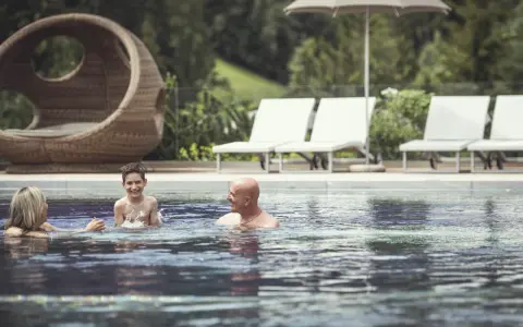 Famiglia felice si diverte in piscina al Cavallino Bianco Family Spa Grand Hotel. Relax e gioia per tutti.