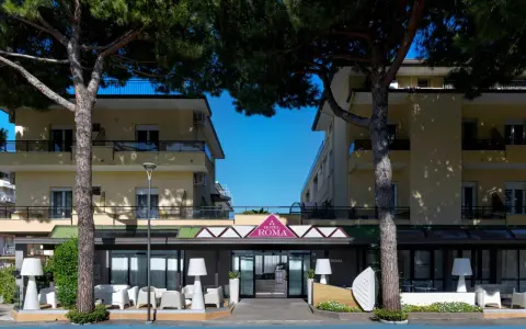 Hotel Roma Cesenatico, con pini marittimi e arredi esterni moderni, invita al relax.