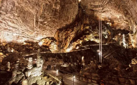 Sentiero illuminato tra stalattiti e stalagmiti in una delle magnifiche grotte in Italia. Un viaggio sotterraneo mozzafiato.