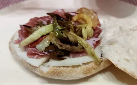 Puccia leccese con salumi, formaggio e verdure grigliate, un sapore autentico del Salento.