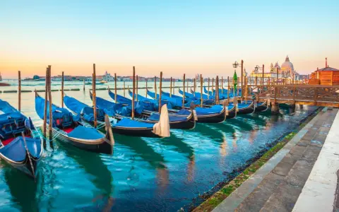 Gondole blu ormeggiate a Venezia, un modo suggestivo per muoversi spendendo poco.