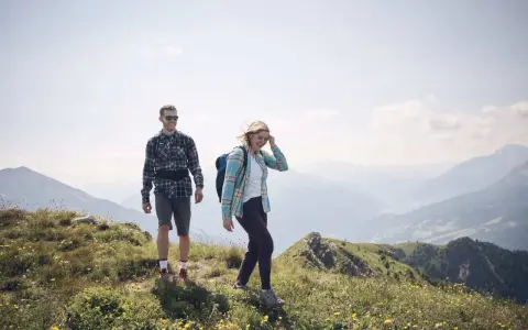 Coppia escursionista sorridente in montagna. L'aria di montagna fa bene al raffreddore, rigenera corpo e mente.