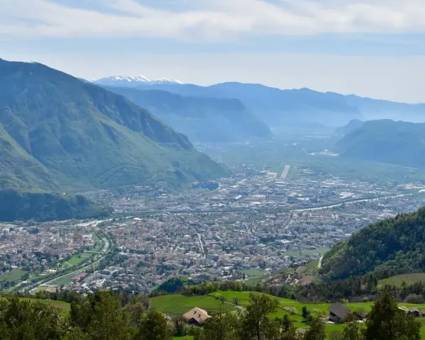 Vista panoramica di Bolzano e della valle, con montagne verdi e innevate sullo sfondo. Perfetto per scoprire cosa fare a Bolzano in un giorno.