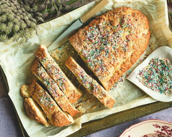 Dolce tipico romagnolo, un ciambellone soffice decorato con zuccherini colorati, pronto per essere gustato.