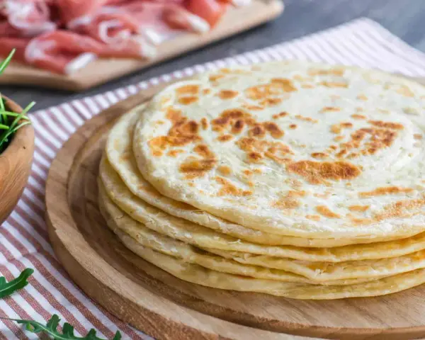 Pila di piadine marchigiane, pronte per essere farcite con rucola e salumi.