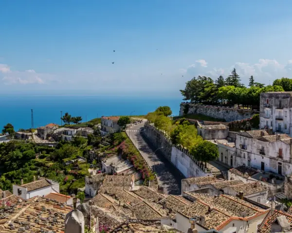 Panoramica di un borgo collinare con vista mare. Per raggiungere l'università Monte Sant'Angelo Napoli, si percorre una strada tortuosa tra case antiche.