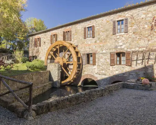 Mulino in pietra con ruota in legno, perfetto per le gite da Tuscany. Un angolo di pace tra alberi e acqua.
