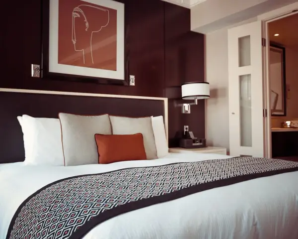 Letto in una camera doppia, con copriletto geometrico e quadro astratto. Il significato di camera doppia è un luogo accogliente.