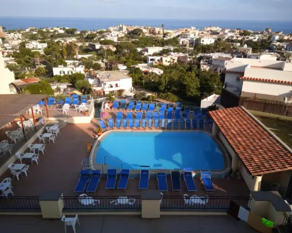 Piscina e lettini prendisole al **hotel tramonto Ischia**, con vista sul mare e sul paese.