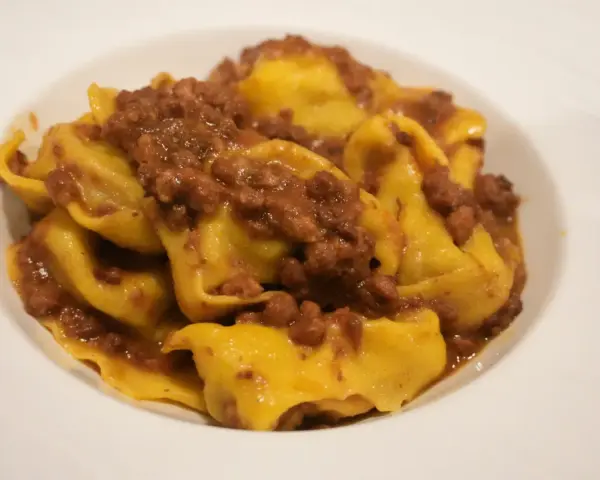 Tortellini fatti in casa con ragù, un classico dei primi piatti romagnoli.