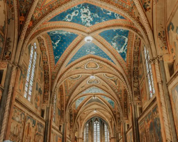 Volte affrescate con cielo stellato e scene sacre nella Basilica Superiore di San Francesco, cuore del centro storico di Assisi.
