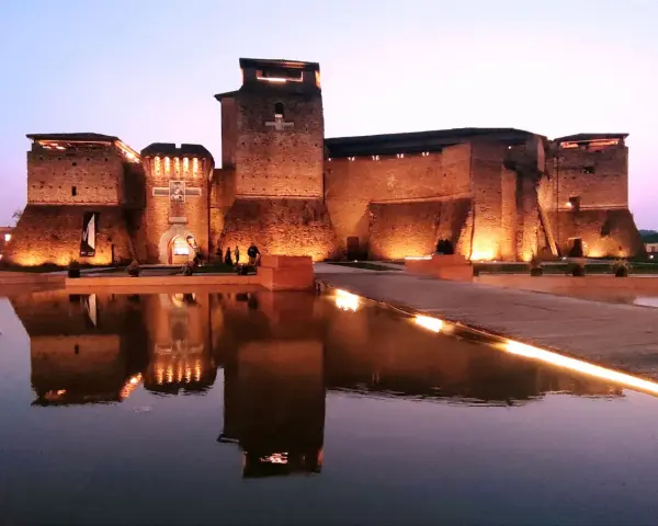 Castello illuminato di sera, riflesso sull'acqua. Un luogo magico che evoca il mondo di Fellini.
