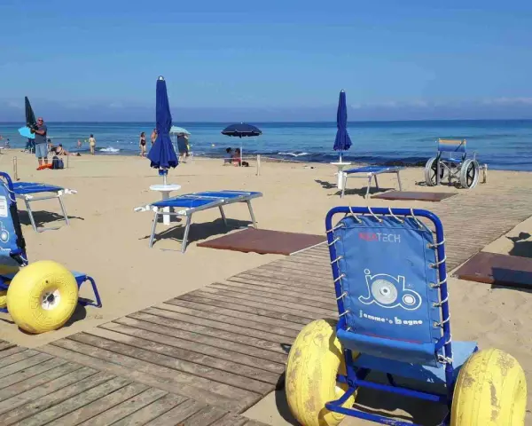 Carrozzine speciali e passerelle per vacanze per disabili con assistenza su una spiaggia attrezzata.