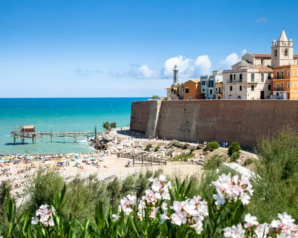 Vista di una spiaggia affollata con un trabucco sul mare e il borgo antico di Termoli. Perfetto per scoprire cosa vedere vicino a Termoli.