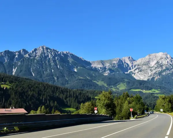 Strada panoramica per viaggi in auto in Europa dall'Italia, con montagne imponenti e boschi verdi.
