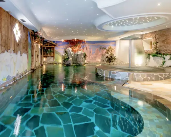 Piscina interna con cascata e decorazioni naturali, un'oasi di relax all'Hotel Sporting Andalo.